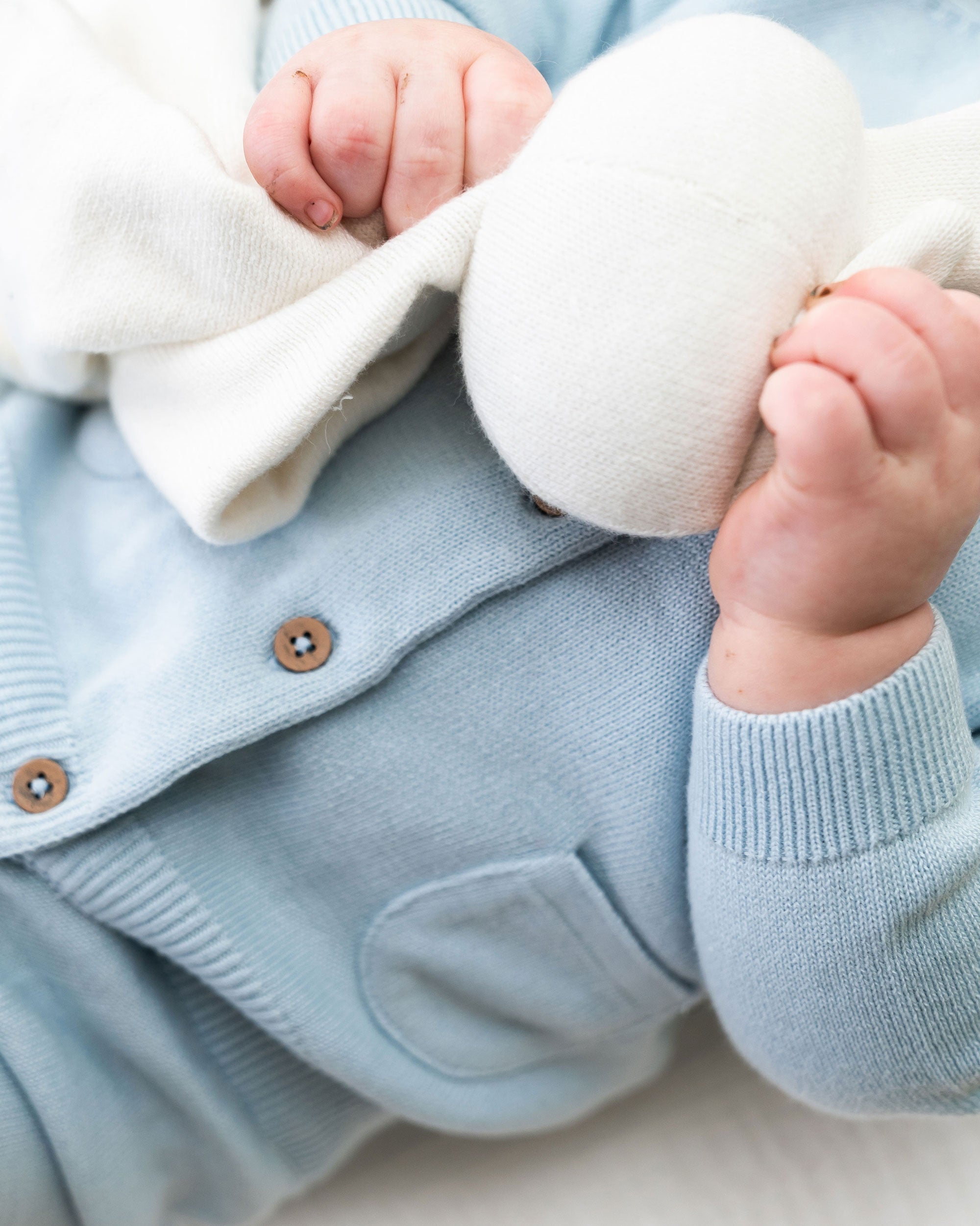 Sky Blue Milan Knit Baby Button Cardigan Sweater (Organic Cotton) on Model holding Lovey Toy