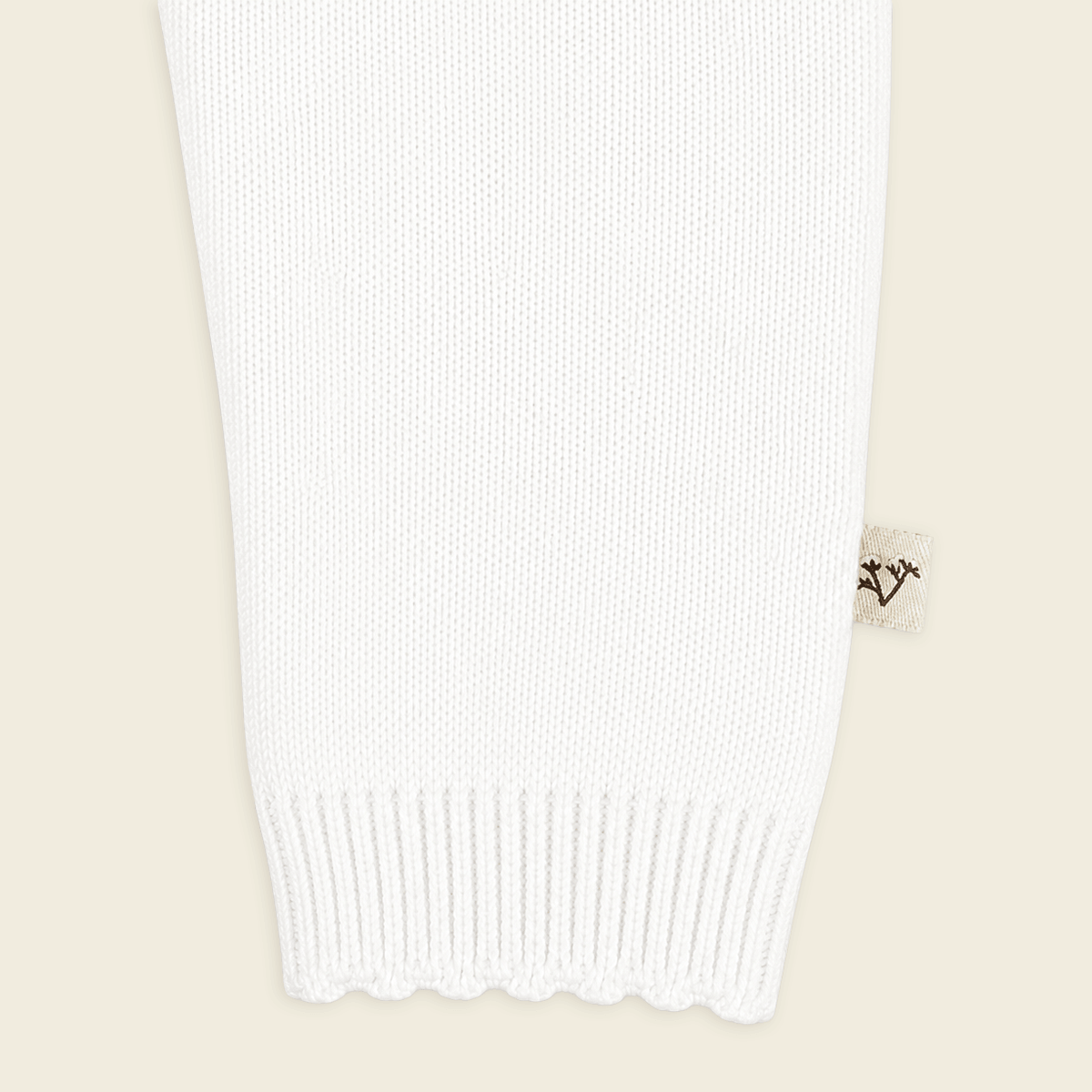 close up of sleeve from milan dove white delicate pointelle knit baby jumpsuit made with organic cotton