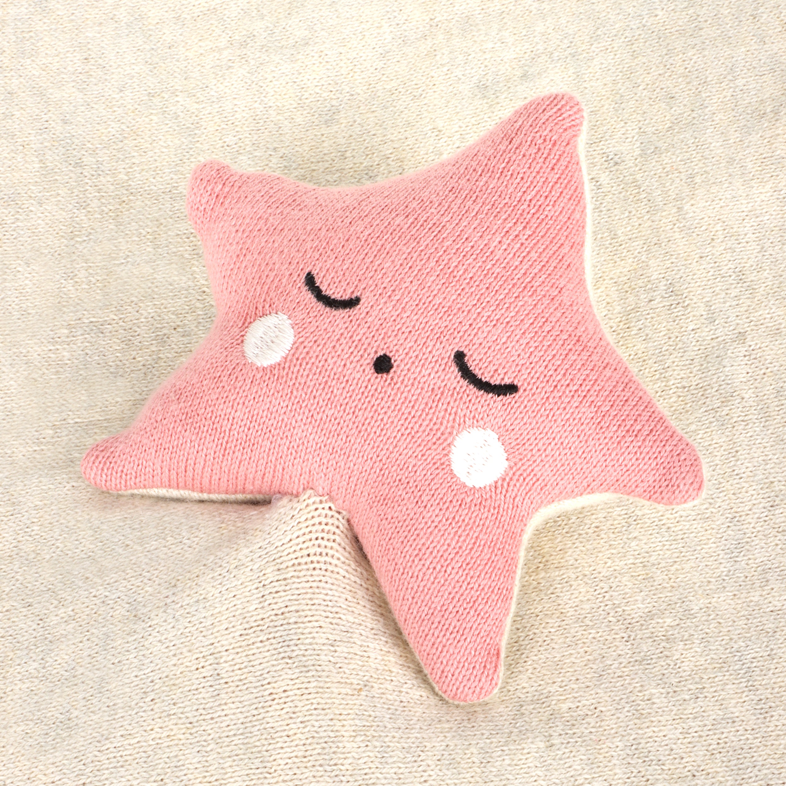 Pink star-shaped toy with a smiling face on a beige background