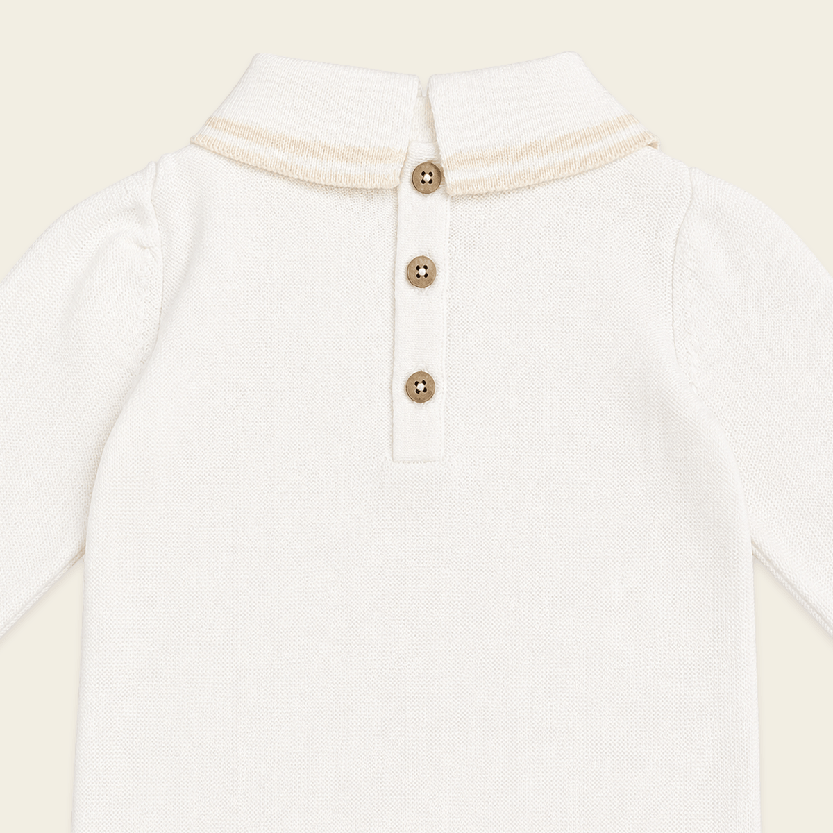 close up back view of milan dove white cable knit baby jumpsuit made of organic cotton