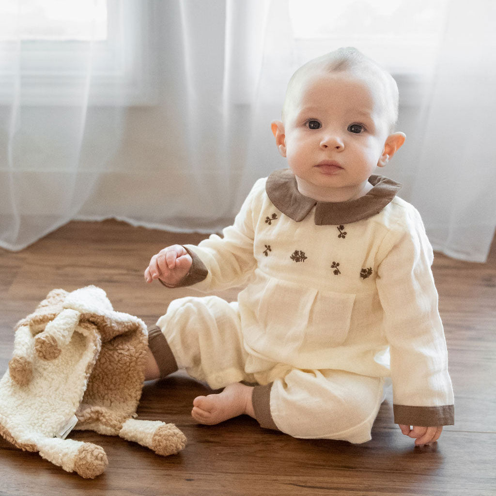 Baby in Organic Embroidered Crinkle Muslin Baby Jumpsuit playing with Viverano lovey toy